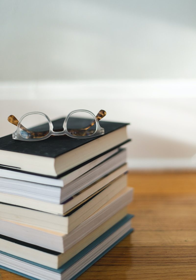 clear framed eyeglasses on top of pile of books